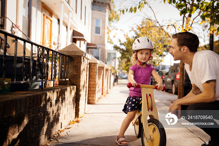 Small girl (2-3) riding on bicycle with father