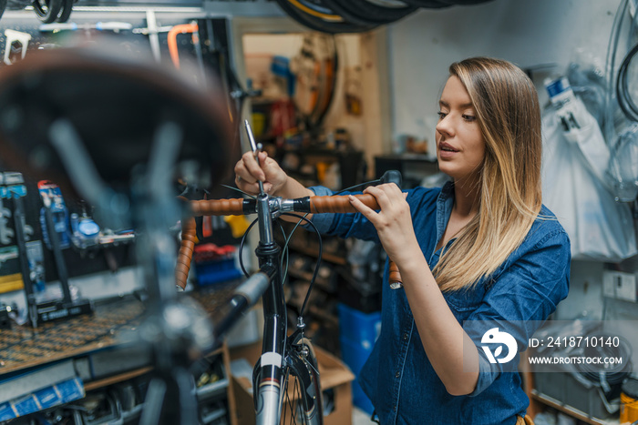 Woman bicycle mechanic is repairing a bike in the workshop