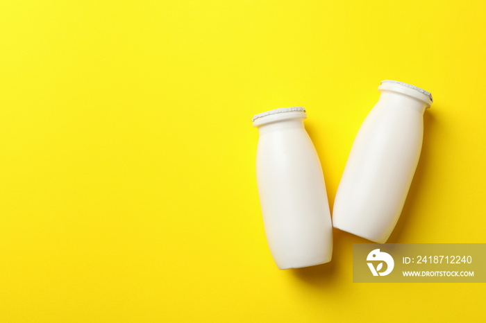 Blank bottles with yogurt on yellow background