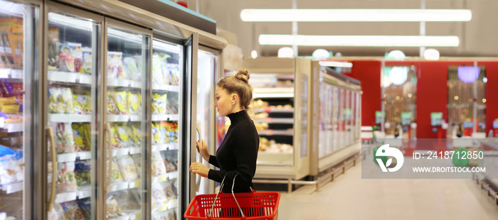 Woman choosing frozen food from a supermarket freezer