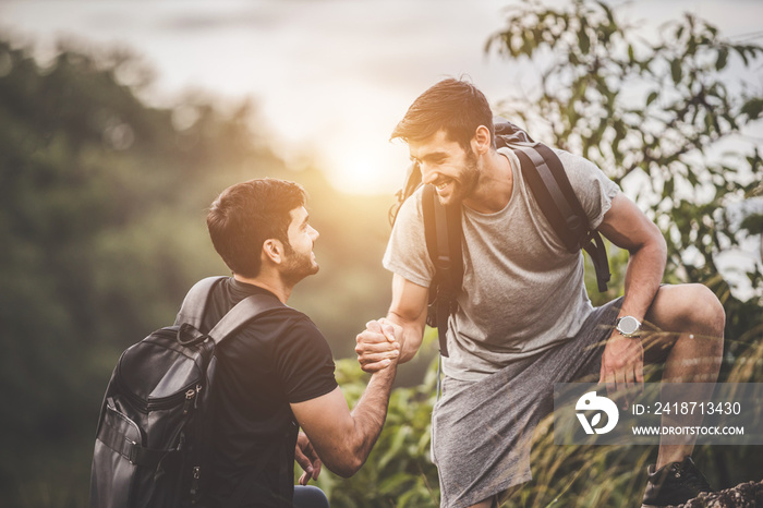 Adventure themed travel and hiking trips - Friends helping each other to climb the mountain intently