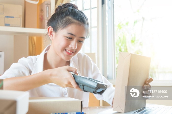 Beautiful lady young worker checking and scanning barcode on package by scanner handheld before deli