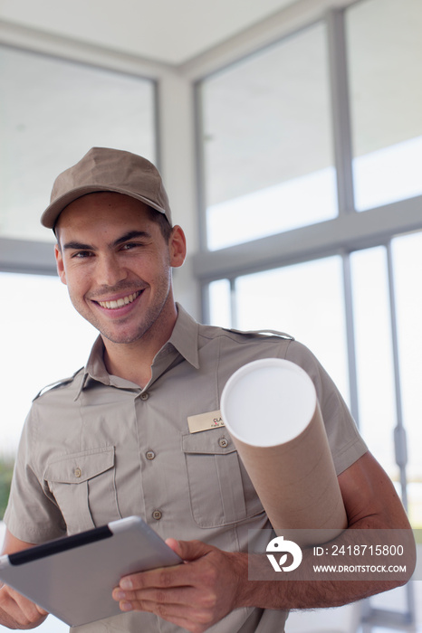 Portrait confident deliveryman with digital tablet and package tube