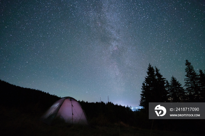 明亮的旅游帐篷在夜空下的黑暗山区露营地发光