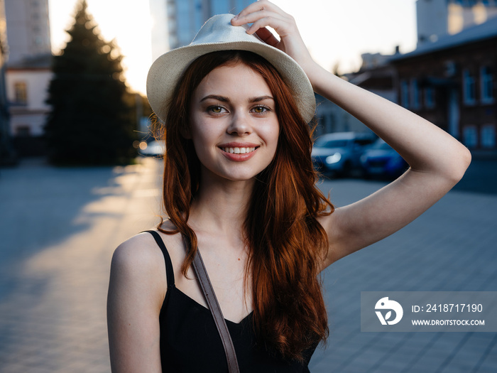 Elegant woman in black dress near the building on the street at sunset