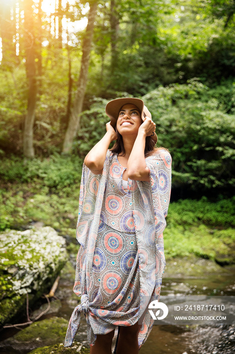 Young woman putting on her hat in forest