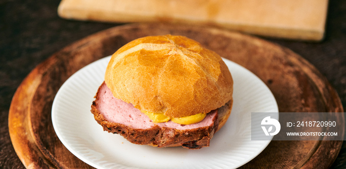 Frischer aufgebackener Leberkäse Fleischkäse in einer Semmel mit Ketchup Senf geschnitten zum mitneh