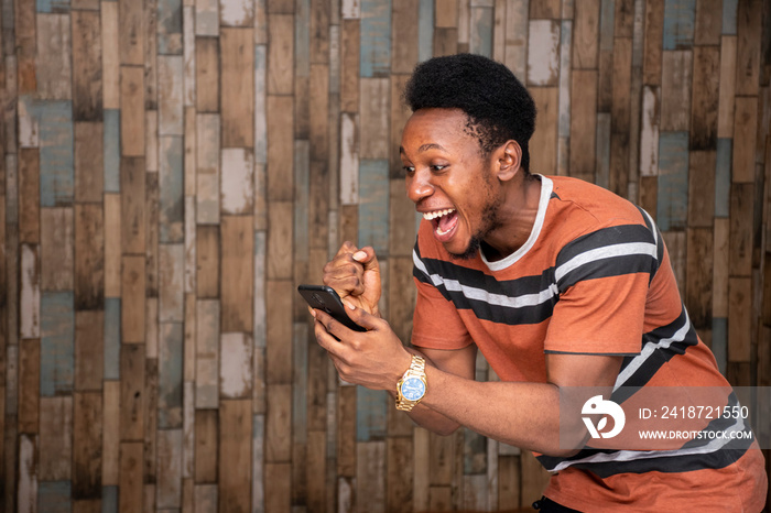 young african man holding his mobile, feeling excited and joyous