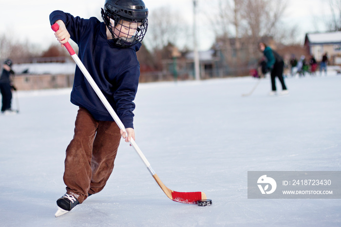 Child playing ice hockey on rink