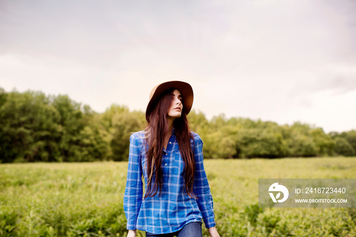 Portrait of young woman standing in meadow