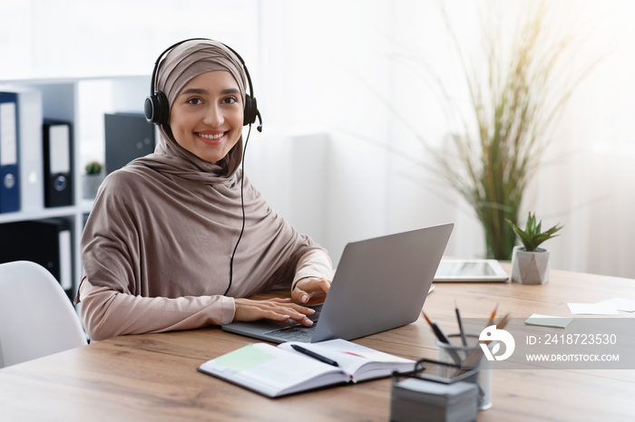 工作场所戴头巾和耳机的阿拉伯女性呼叫中心操作员
