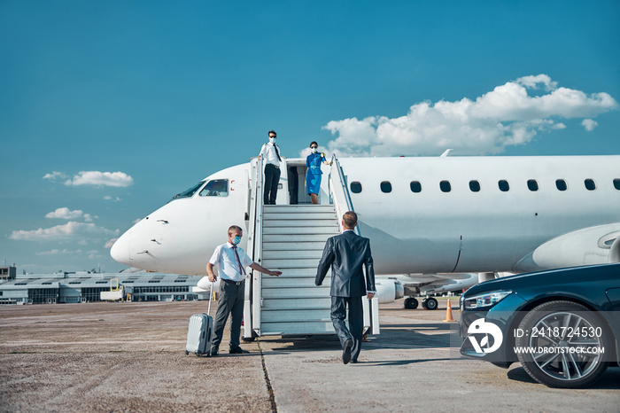 Businessman with assistant getting on plane during quarantine