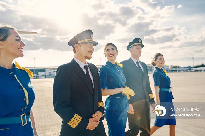 快乐的女乘务员和航空公司飞行员继续前进