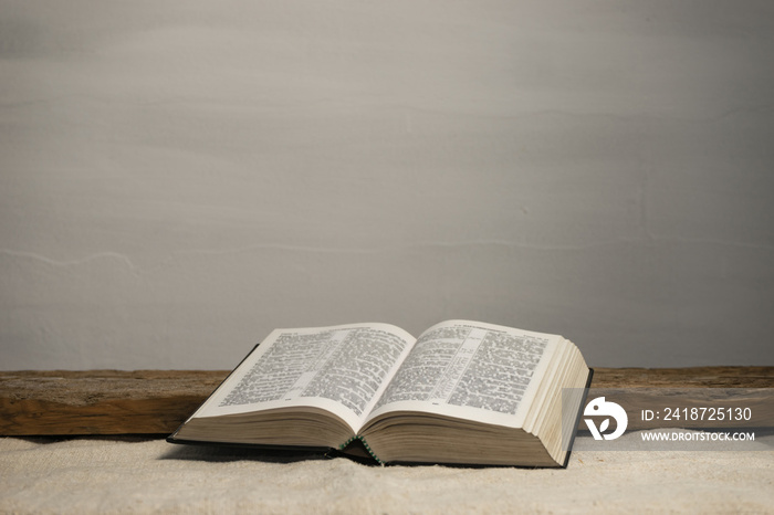 Open Holy Bible on a old wooden table and white wall background. Religion concept.