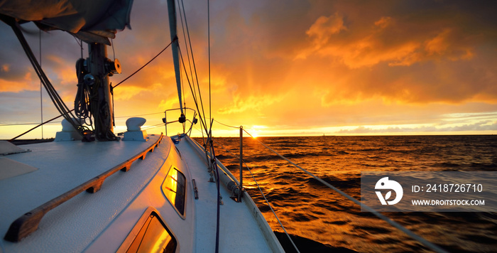 日落时，白色游艇在公海航行。从甲板到船头、桅杆和帆的景色。史诗般的clo