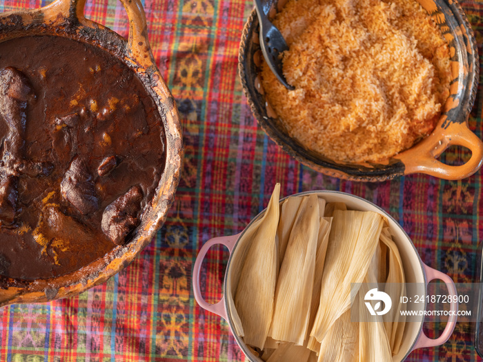 Overhead image of three traditional, Indigenous meals: mole, rice, and tamales