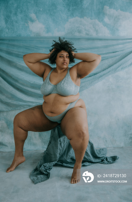 full body portrait of a plus size afro-indigenous person sitting with hands in hair