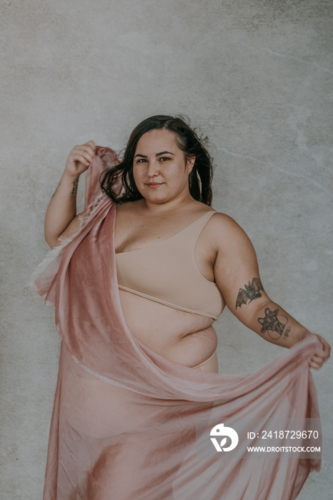 plus size metis woman wearing nude bra and underwear dancing with pink fabric