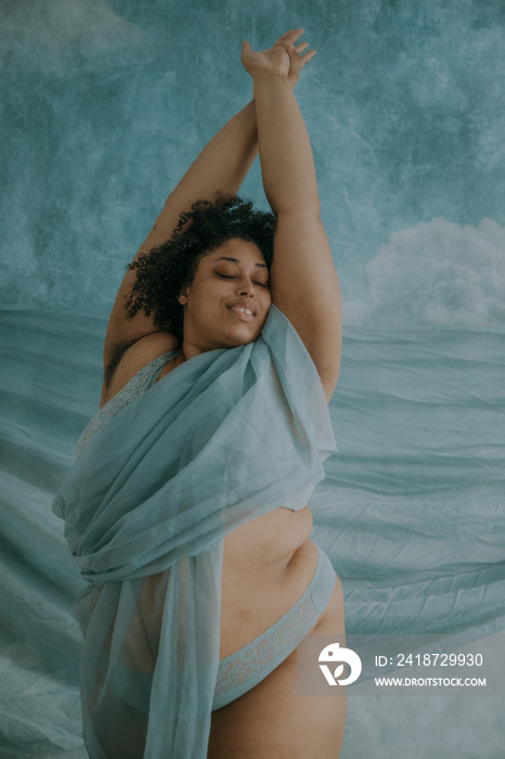 portrait of a plus size afro indigenous non-binary person stretching overhead