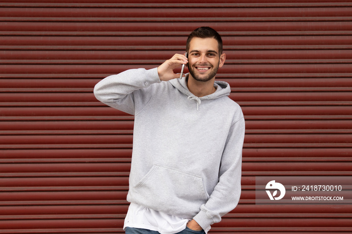 urban young man in casual style with mobile phone in garage blind