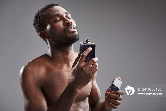 Content young afro American man using his cologne with pleasure