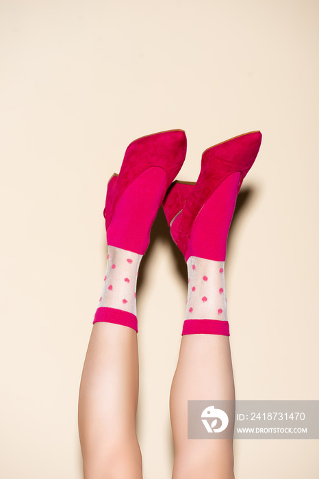 cropped view of female legs in pink retro socks and shoes on beige background