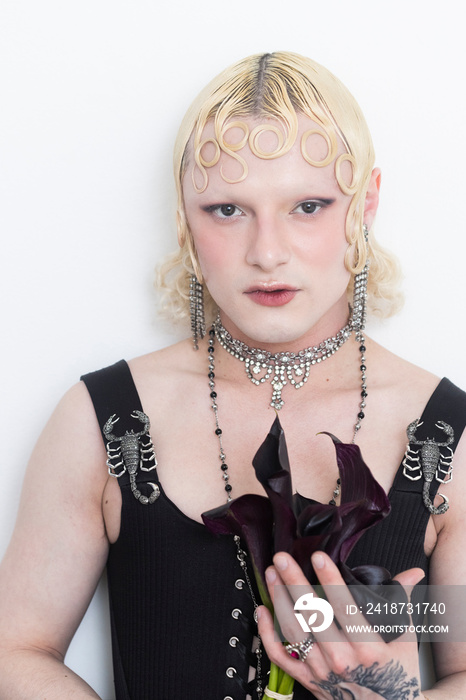 close up beauty of non-binary person wearing black dress and holding cflowers