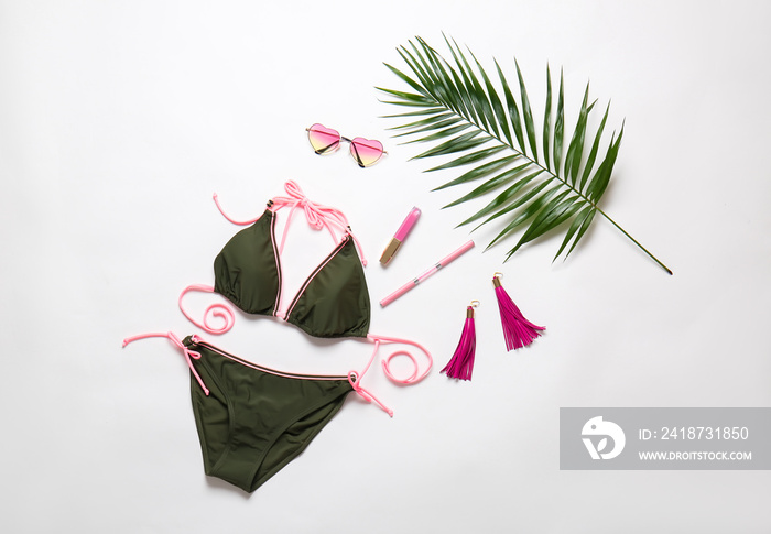 Female swimsuit with accessories and tropical leaf on white background