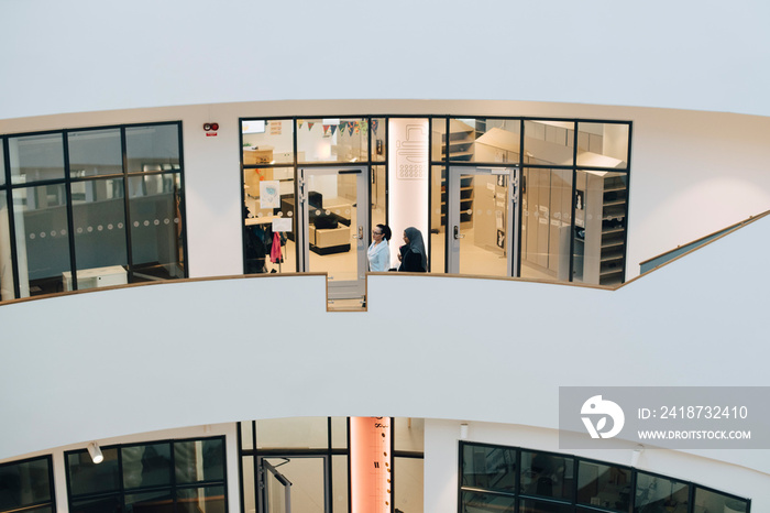 High angle view of teacher and student standing in corridor at university