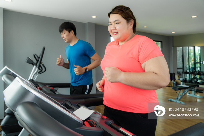 两名亚洲教练男子和超重女子在健身房的跑步机上锻炼，教练砰砰作响