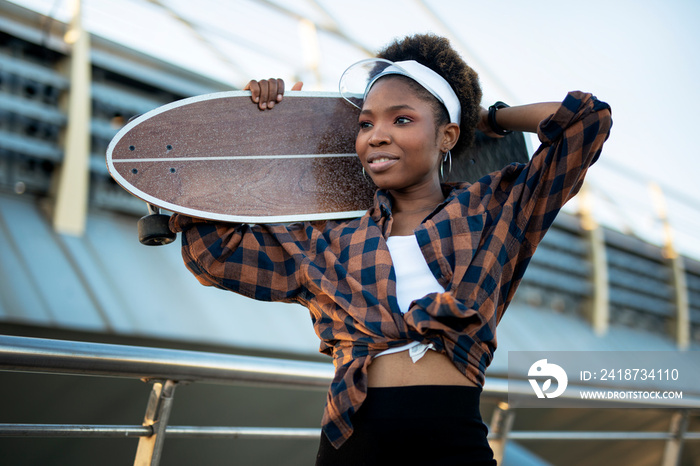快乐的非裔美国滑板女性肖像。年轻时尚的滑板女性