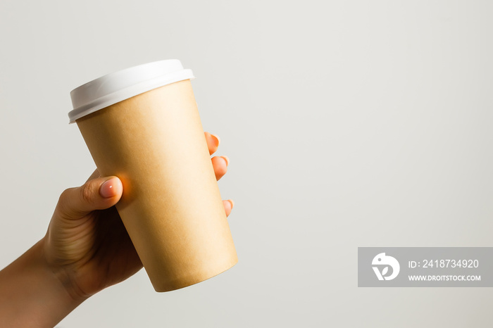 Creative mock up image of woman hand holding craft paper coffee cup with copy space isolated on whit