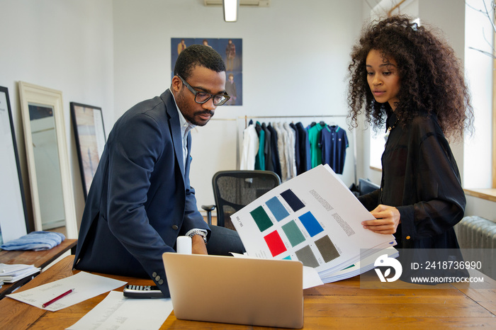 Fashion designers reviewing fabric swatches by laptop