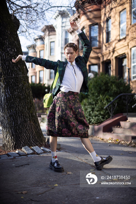 non-binary caucasian person with short hair dancing on Brooklyn sidewalk