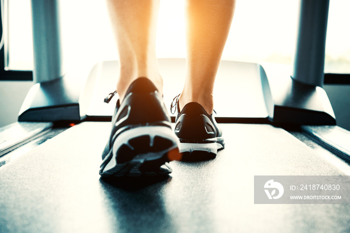 Close up of people who exercising on treadmill. Close-up of woman legs walking by treadmill in sport