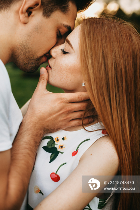 一对英俊的情侣在落日余晖下约会时接吻的侧视图。