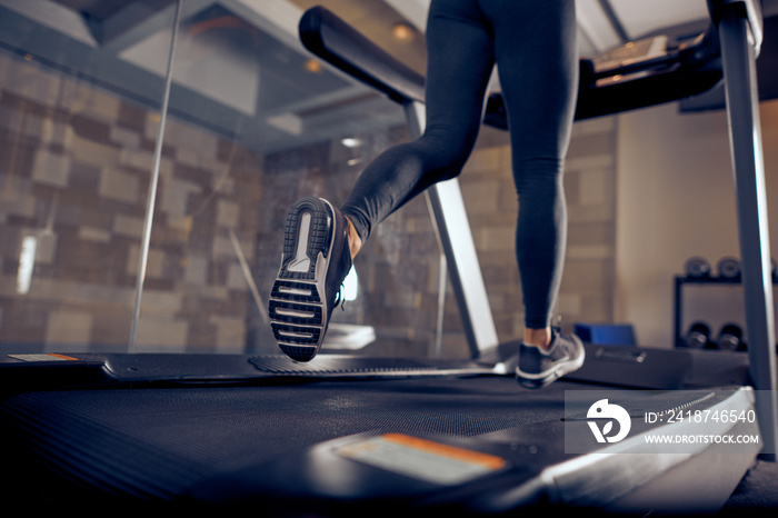 Close up of womans legs running on treadmill. Gym interior.