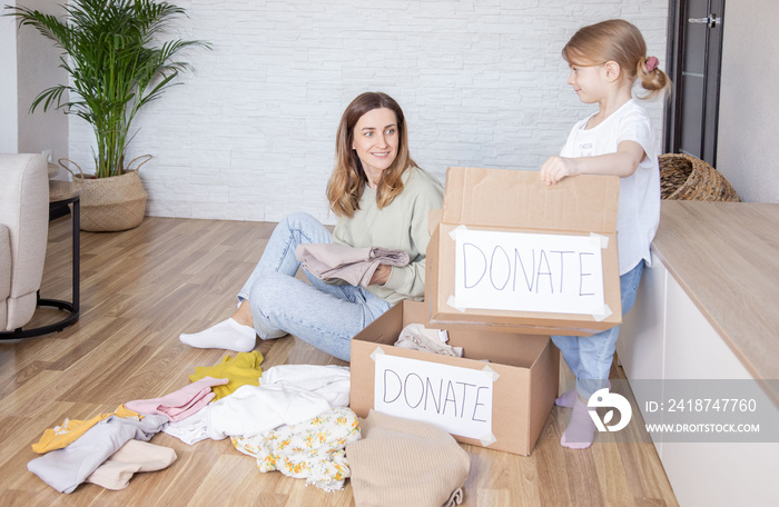 Mother with daughter packing clothes for donations.