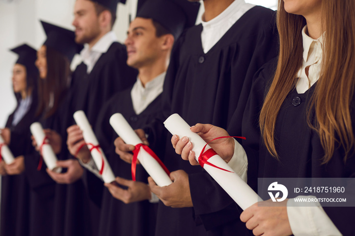 毕业典礼上，身穿黑色礼服的大学生手持传统文凭卷轴