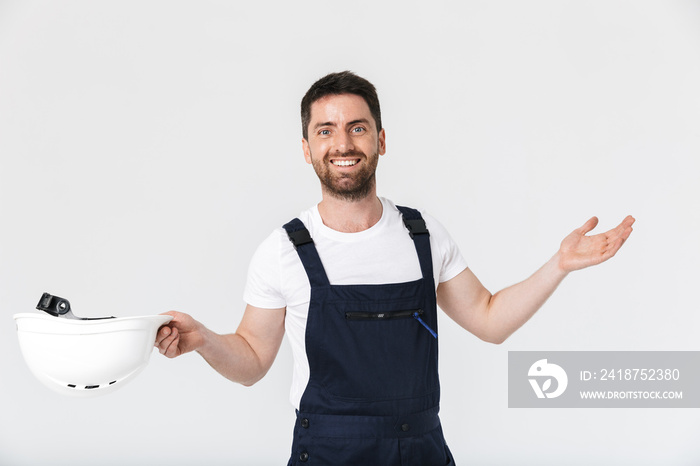 Confident bearded builder man wearing overalls standing