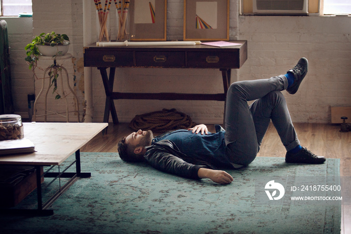 Young man lying down on floor in living room