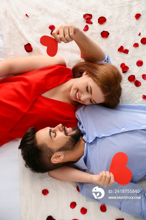 幸福的红心夫妇躺在家里的床上。庆祝圣瓦伦丁节