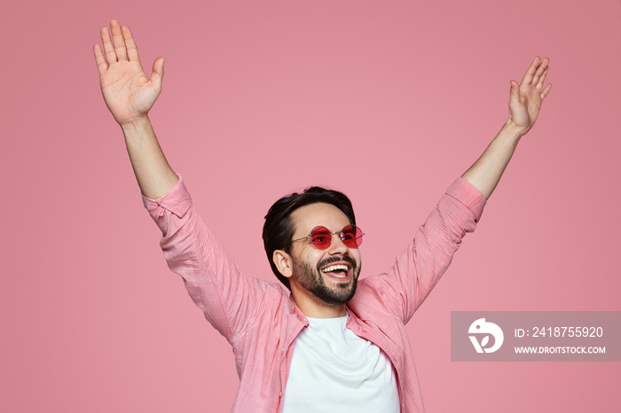 Cheerful bearded man, sharing happiness and raising his hands in the air, having fun and posing over