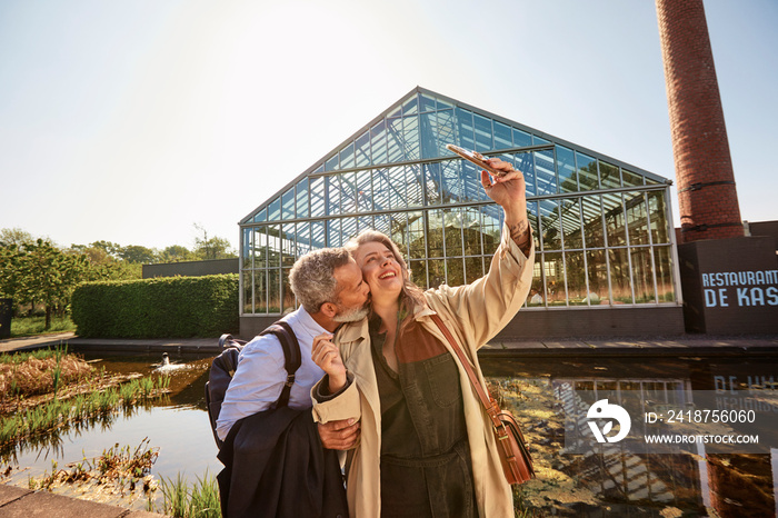 Mature couple kissing for smartphone selfie