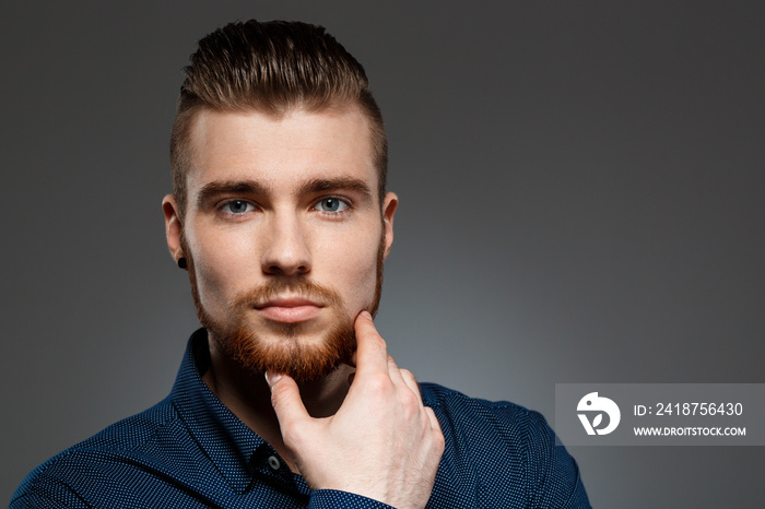 Young successful businessman posing over dark background. Copy space.