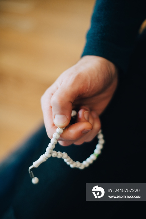 Cropped image of mature man with prayer beads at home