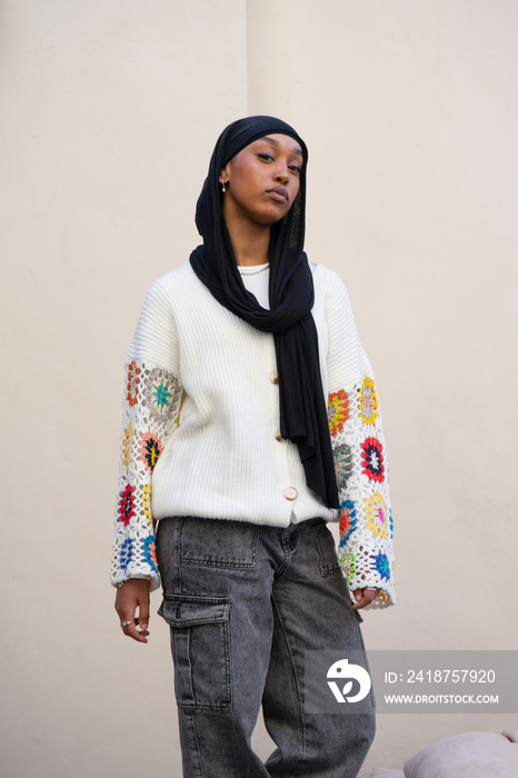 Portrait of woman wearing hijab standing against wall