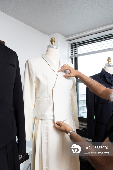 brown skin mans hands working on tailor dress form