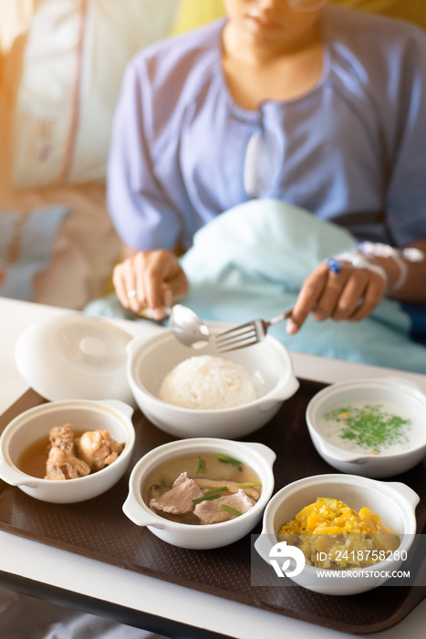 Woman wearing a blue dress, eating on the bed in the hospital