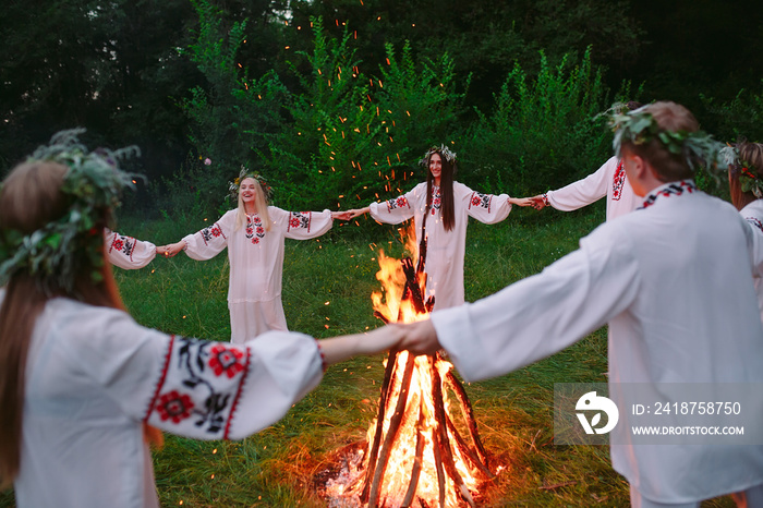 仲夏。穿着斯拉夫服装的年轻人在森林里围着篝火跳舞。